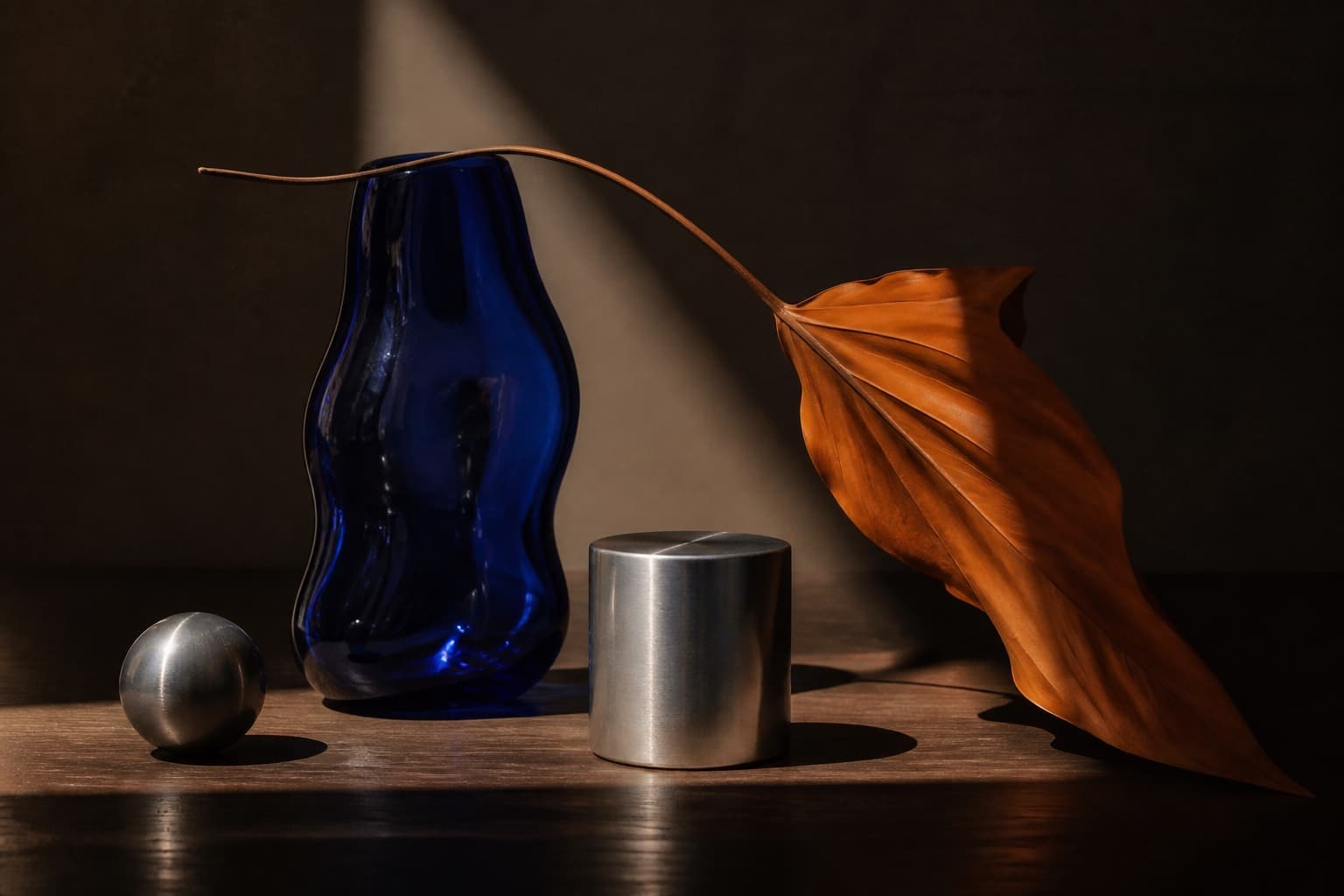 Still life com vidro azul, metal e folha em tons quentes